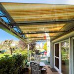 seitliche Terrasse mit Glasdach und Beschattung